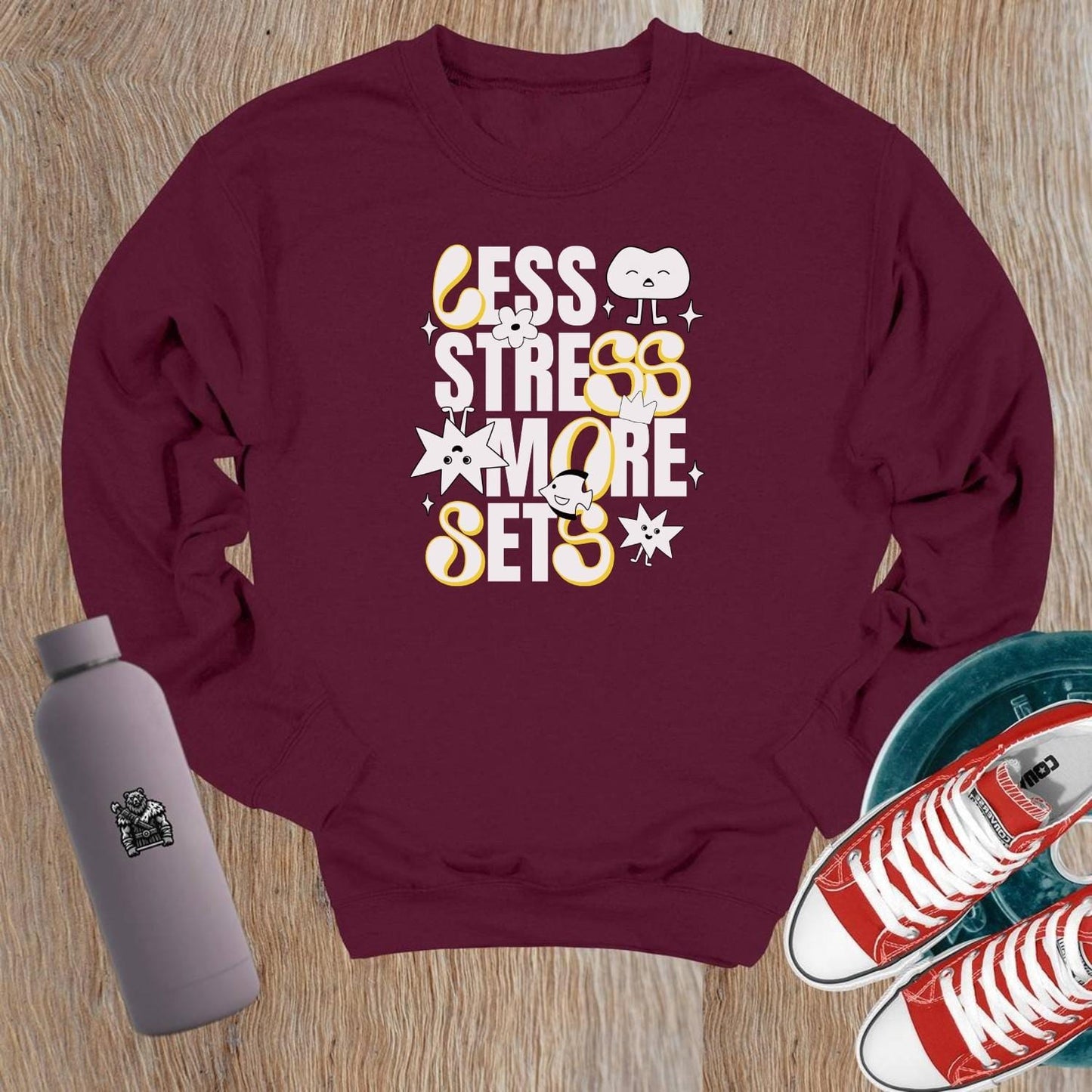 Alt text: "Vibrant crewneck sweatshirt with playful fitness graphics 'Less Stress, More Sets!' Perfect for gym workouts and casual wear."