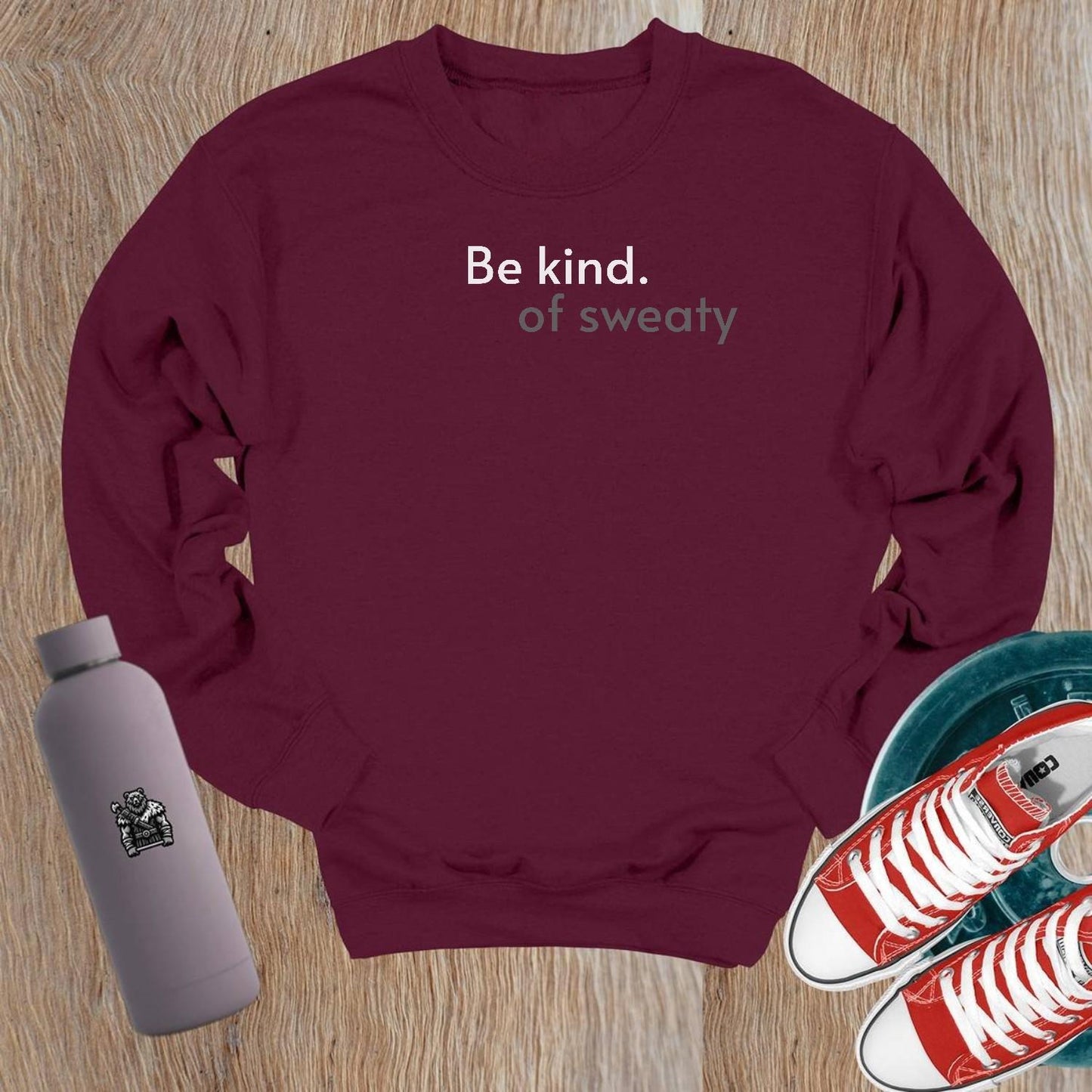 "Stylish crewneck sweatshirt with 'Be kind. of sweaty.' text, perfect for workouts or lounging; combines comfort and motivation."
