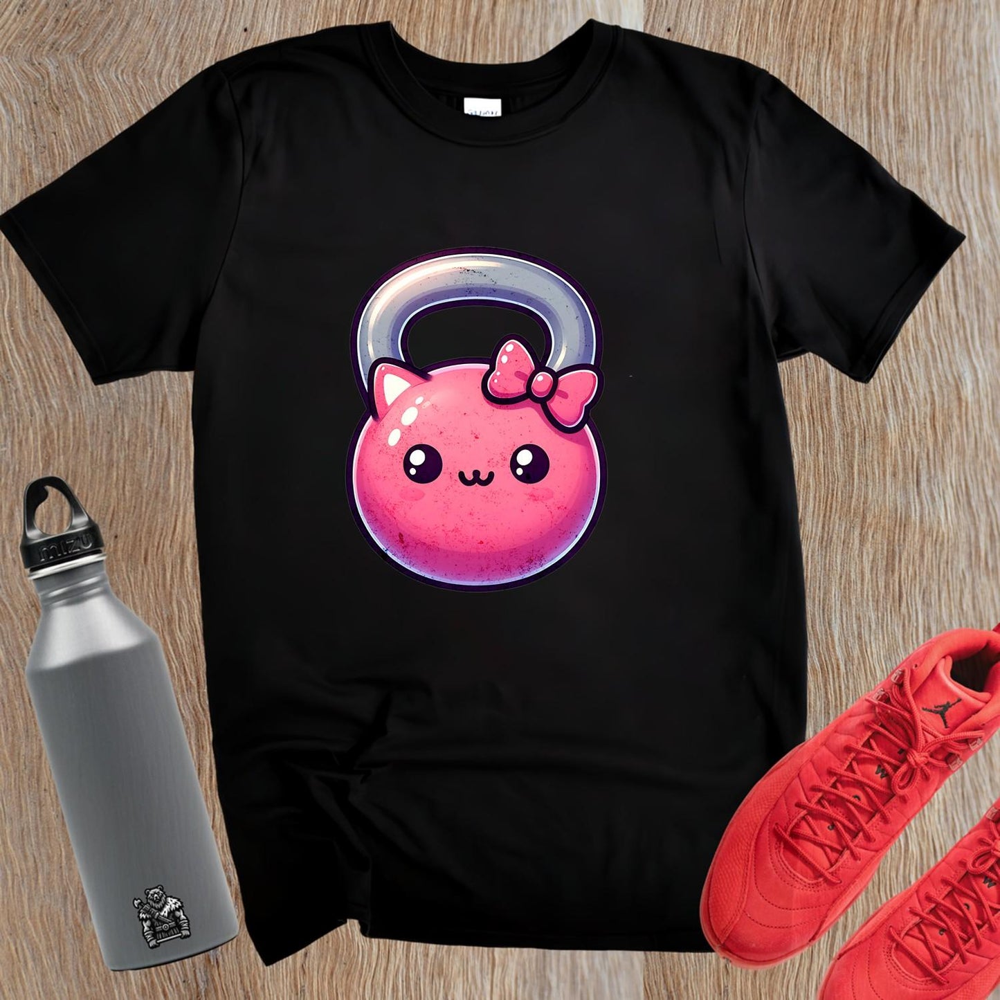 "Adorable pink kettlebell T-shirt with a cute cat face and bow, perfect for gym lovers. Stylish workout gear for fitness enthusiasts."