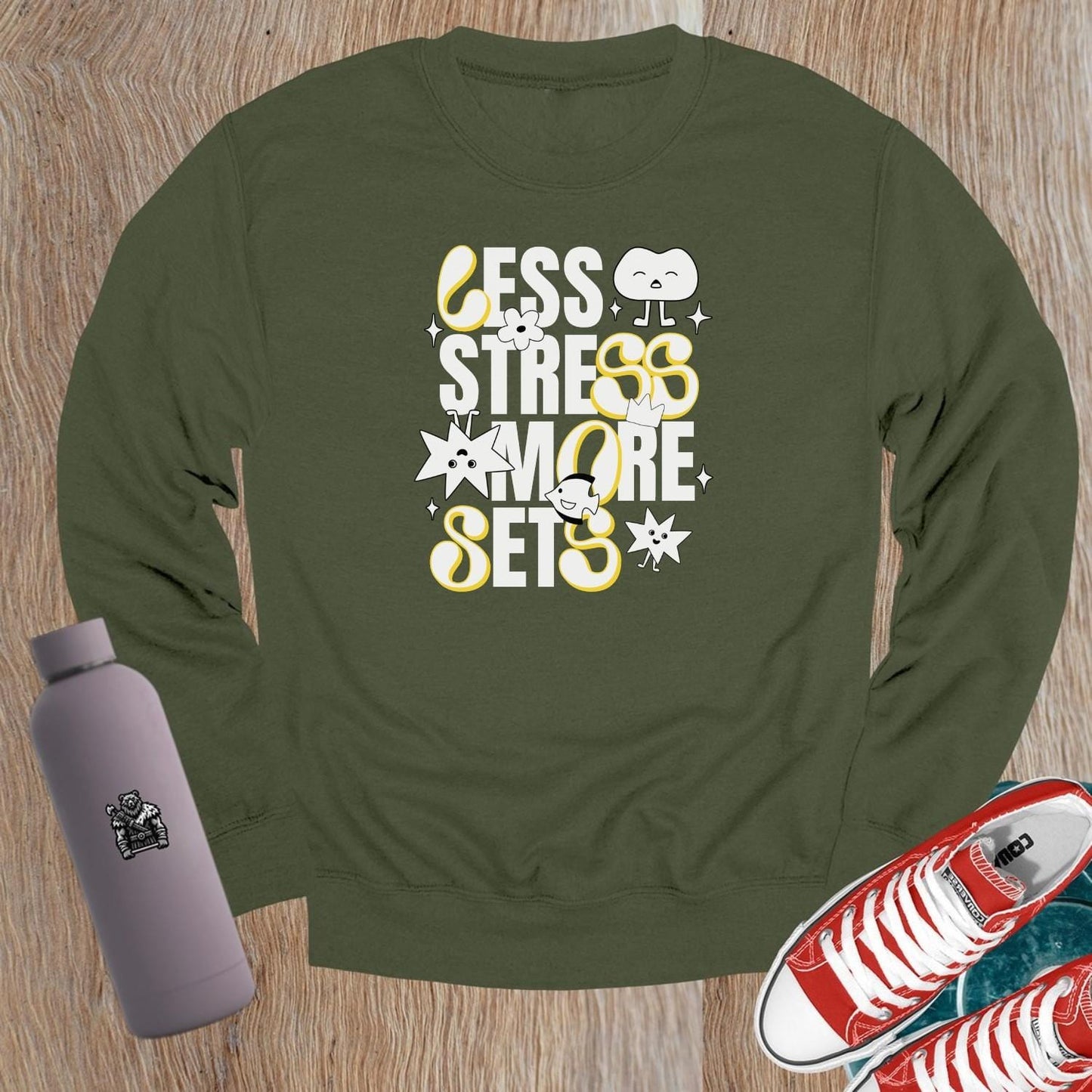 Alt text: "Vibrant crewneck sweatshirt with playful fitness graphics 'Less Stress, More Sets!' Perfect for gym workouts and casual wear."