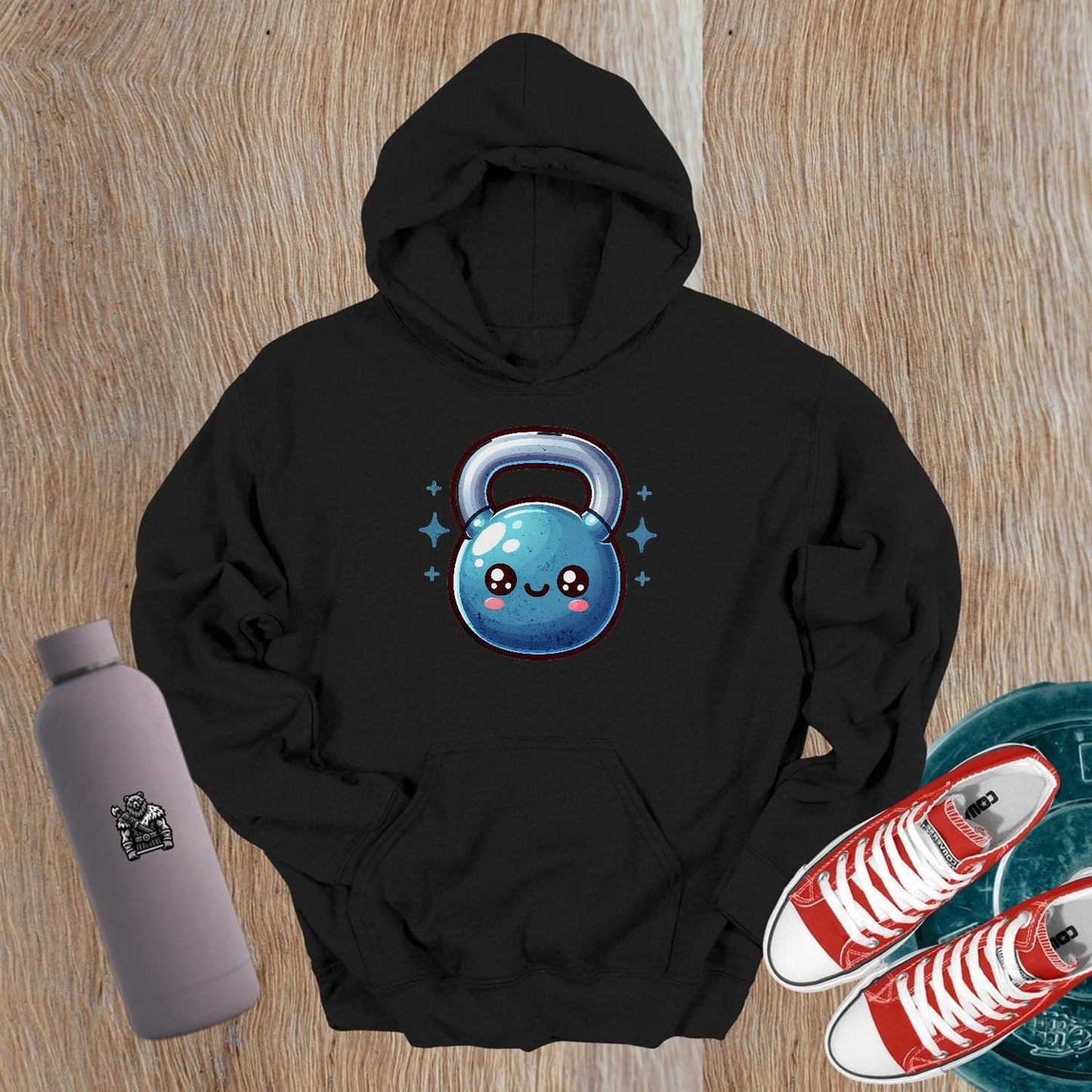 "Adorable fitness hoodie featuring a smiley kettlebell graphic, perfect for workouts or casual wear. Stylish and cozy gym apparel."