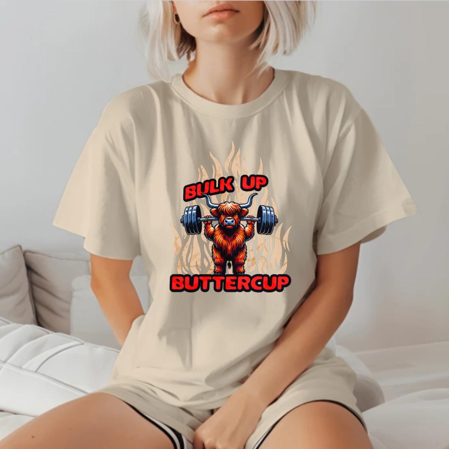Alt text: "Bulk Up Buttercup T-shirt featuring a fierce weightlifting Highland cow surrounded by vibrant flames, perfect for gym enthusiasts."