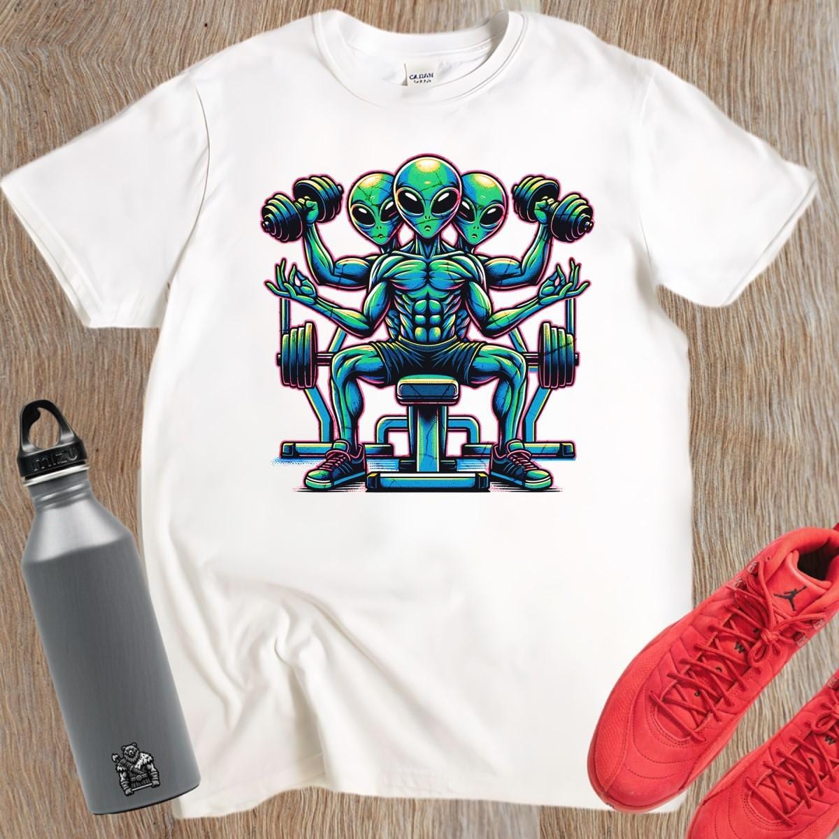 "Colorful graphic of powerful aliens lifting weights on a gym t-shirt, inspiring fitness goals and showcasing unique workout style."