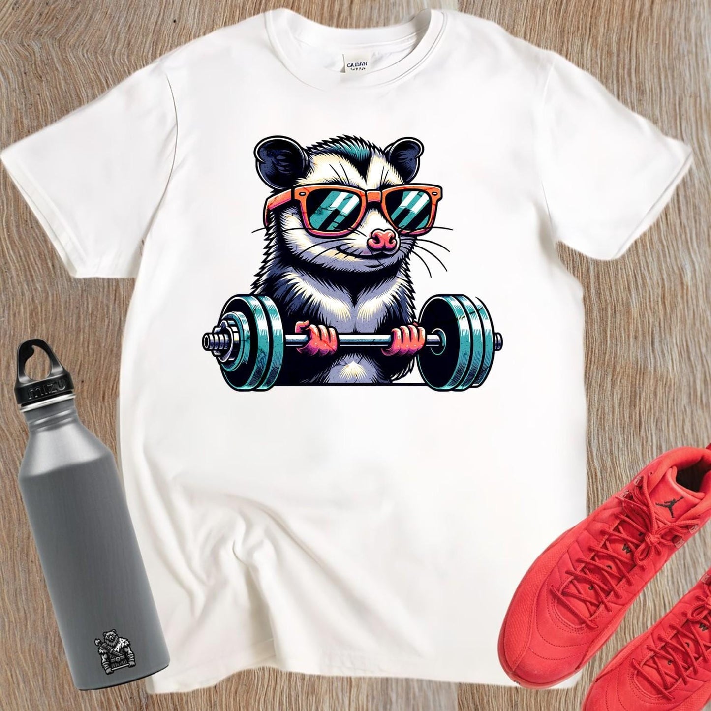 "Playful gym T-shirt featuring a cool possum lifting weights in stylish sunglasses, perfect for fitness enthusiasts and workout motivation."