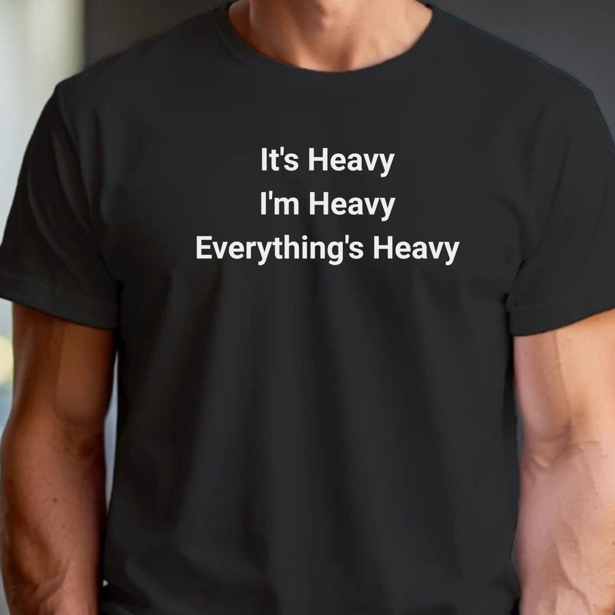 Alt text: "Bold black and white gym T-shirt featuring the motivational phrase 'It's Heavy, I'm Heavy, Everything's Heavy' for fitness enthusiasts."
