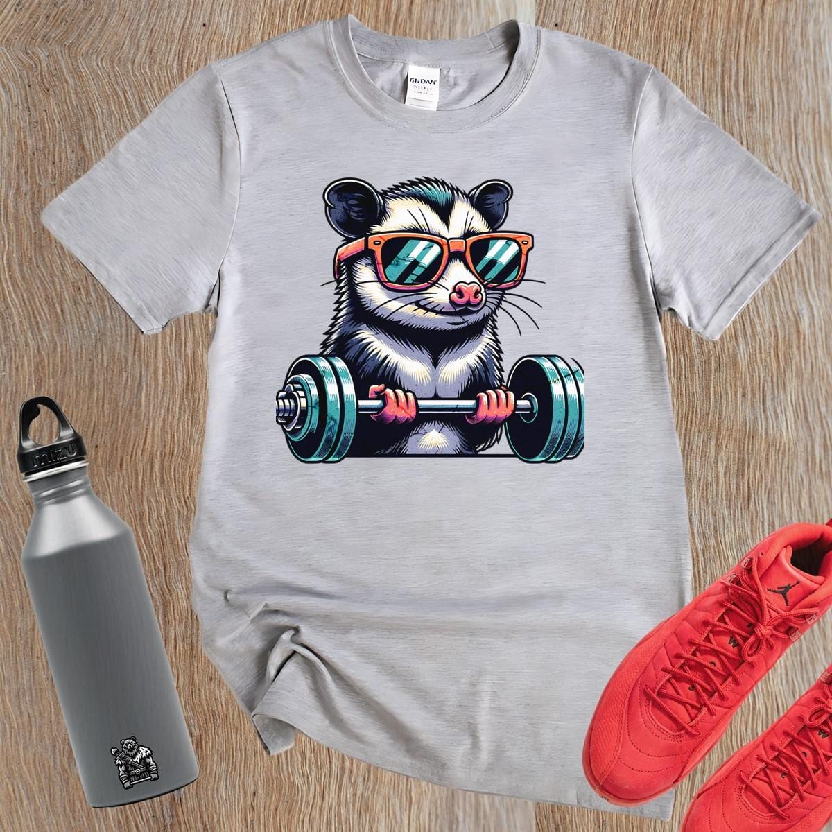 "Playful gym T-shirt featuring a cool possum lifting weights in stylish sunglasses, perfect for fitness enthusiasts and workout motivation."