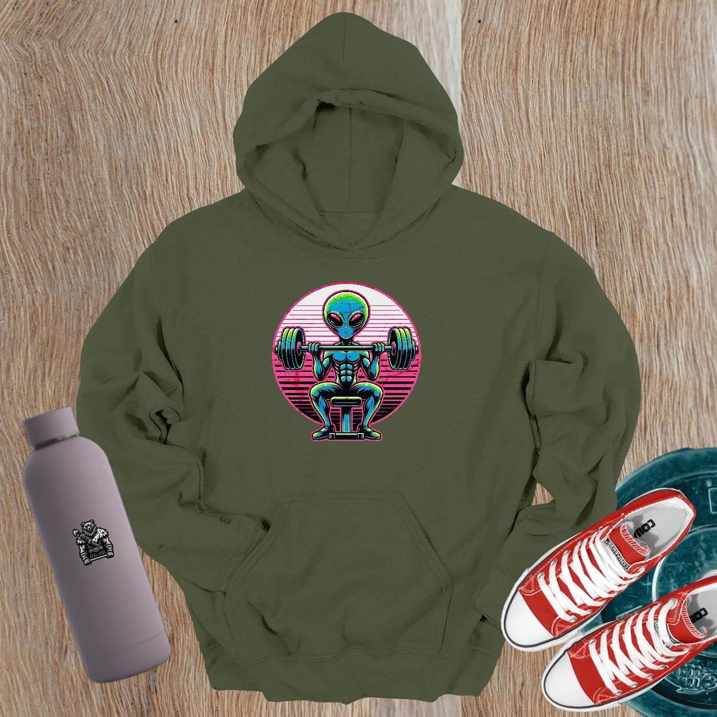 "Vibrant Alien Strength Hoodie featuring a bold alien lifting weights design, perfect for gym enthusiasts seeking unique workout apparel."