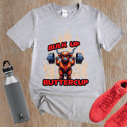 Alt text: "Bulk Up Buttercup T-shirt featuring a fierce weightlifting Highland cow surrounded by vibrant flames, perfect for gym enthusiasts."