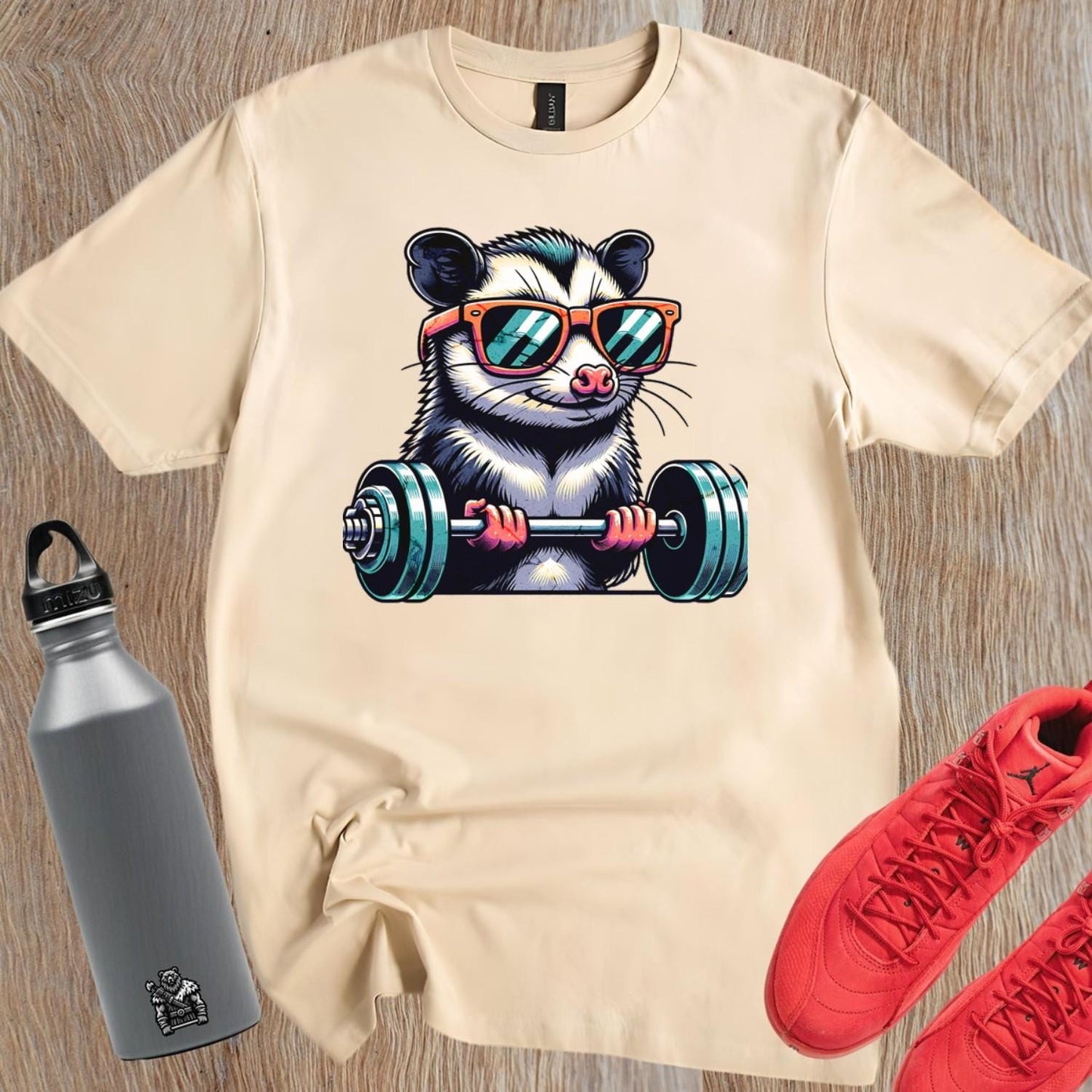 "Playful gym T-shirt featuring a cool possum lifting weights in stylish sunglasses, perfect for fitness enthusiasts and workout motivation."